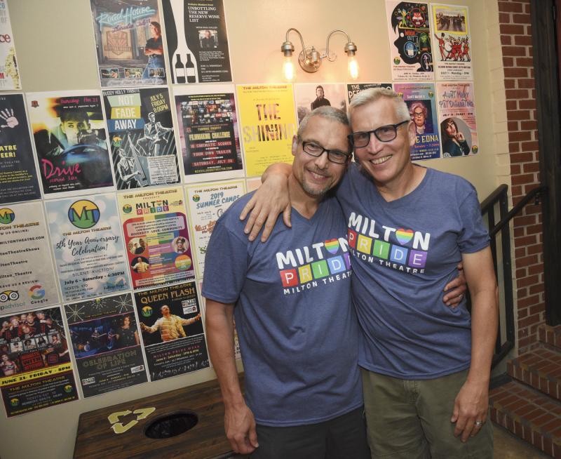 Jeff Wilkinson, left, and Bill Rogers wear Milton Pride T-shirts at the wall of posters illustrating the diverse shows at Milton Theatre.